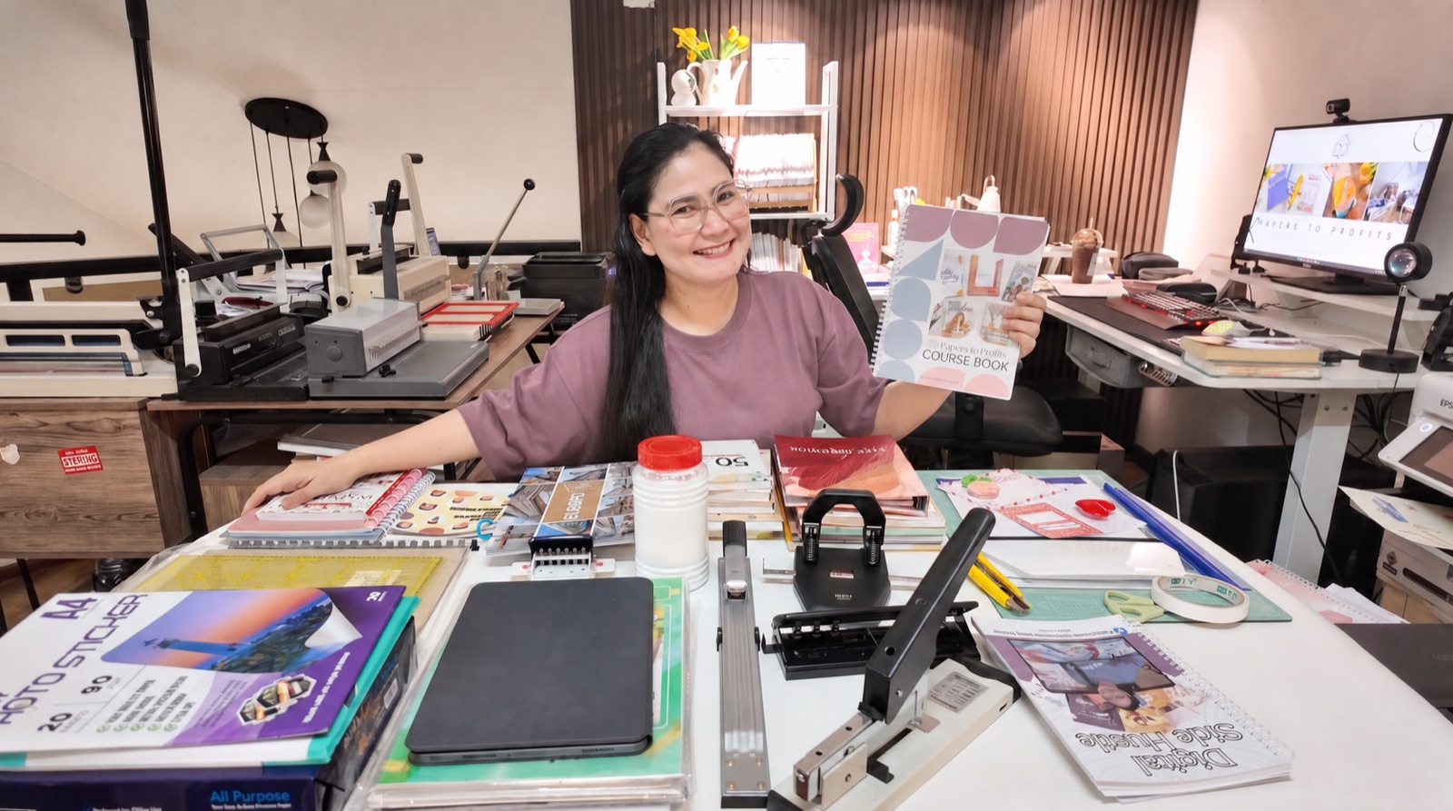 Grace holding the Papers to Profits Course Book in her home workshop